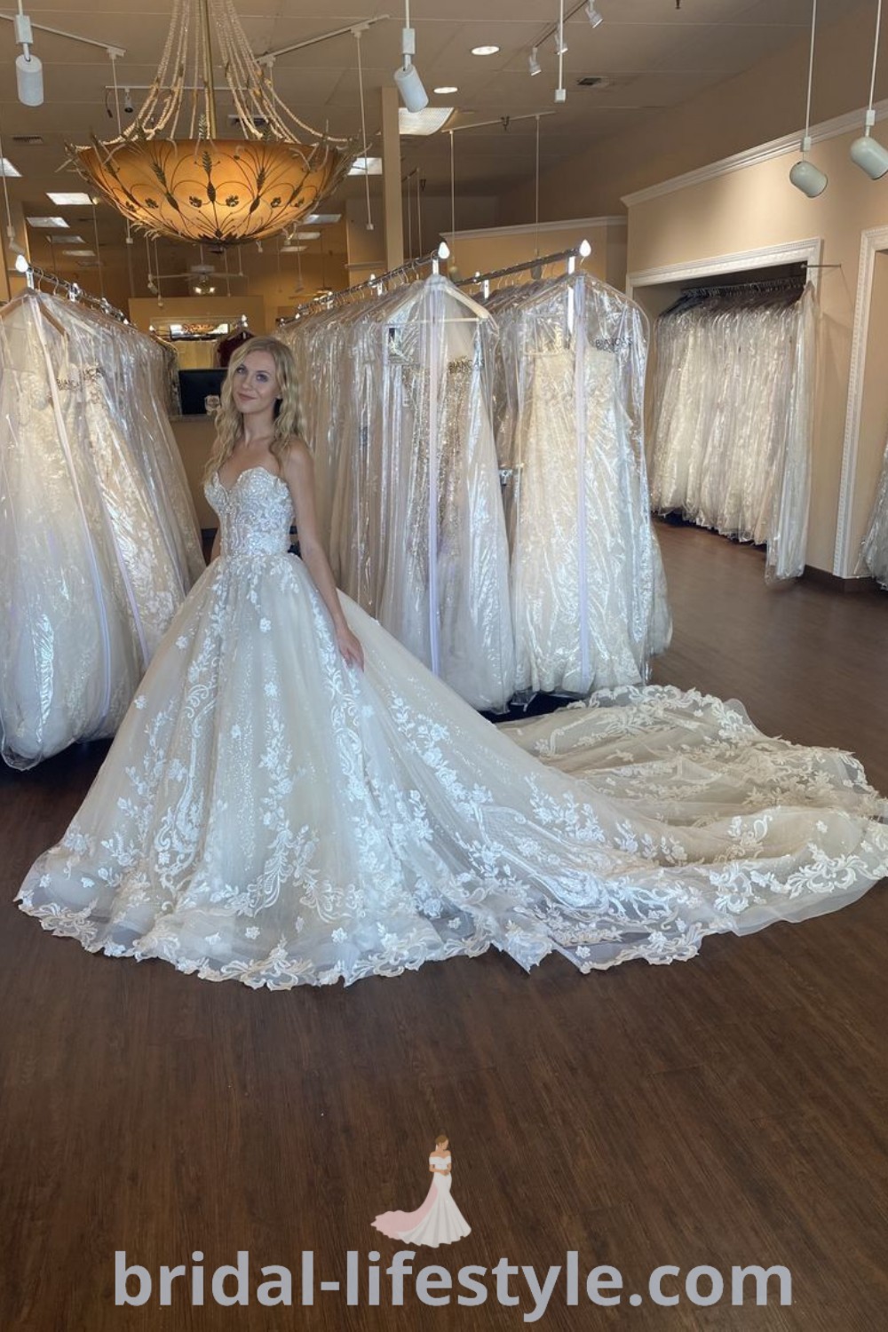 An elegant woman stands in front of stunning wedding dresses with train ball gowns, showcasing beautiful designs ideal for every dreamy bride. Featuring styles like sleeveless ball gowns and corset wedding dresses, these enchanting gowns are perfect for the special day. Explore the trends and aesthetic ideas at bridal-lifestyle.com.