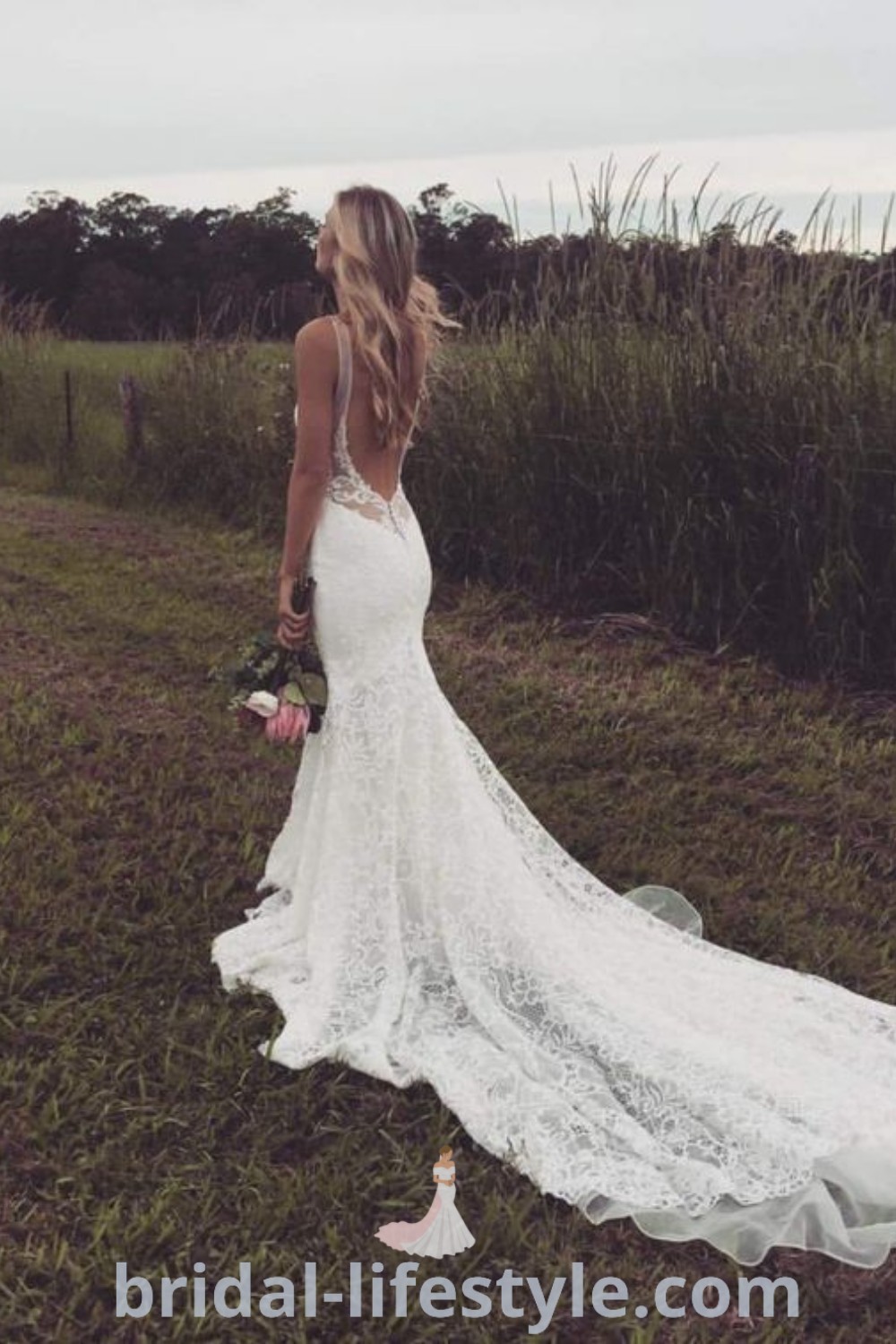A woman in a backless wedding dress standing on the grass with her back to the camera, showcasing elegant bridal style and inspiration looks for the special day. The scene features burnt orange bridesmaid dresses, highlighting trending bridal aesthetics at bridal-lifestyle.com.