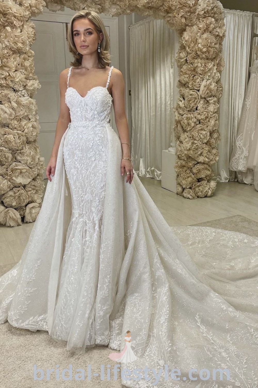 An elegant woman standing in front of a wedding dress featuring styles like the Mori Lee Bridal 2022 and Madi Lane Wedding Dress Prestyn, showcasing inspiration looks for brides. Find the best wedding dress aesthetic ideas for every bride