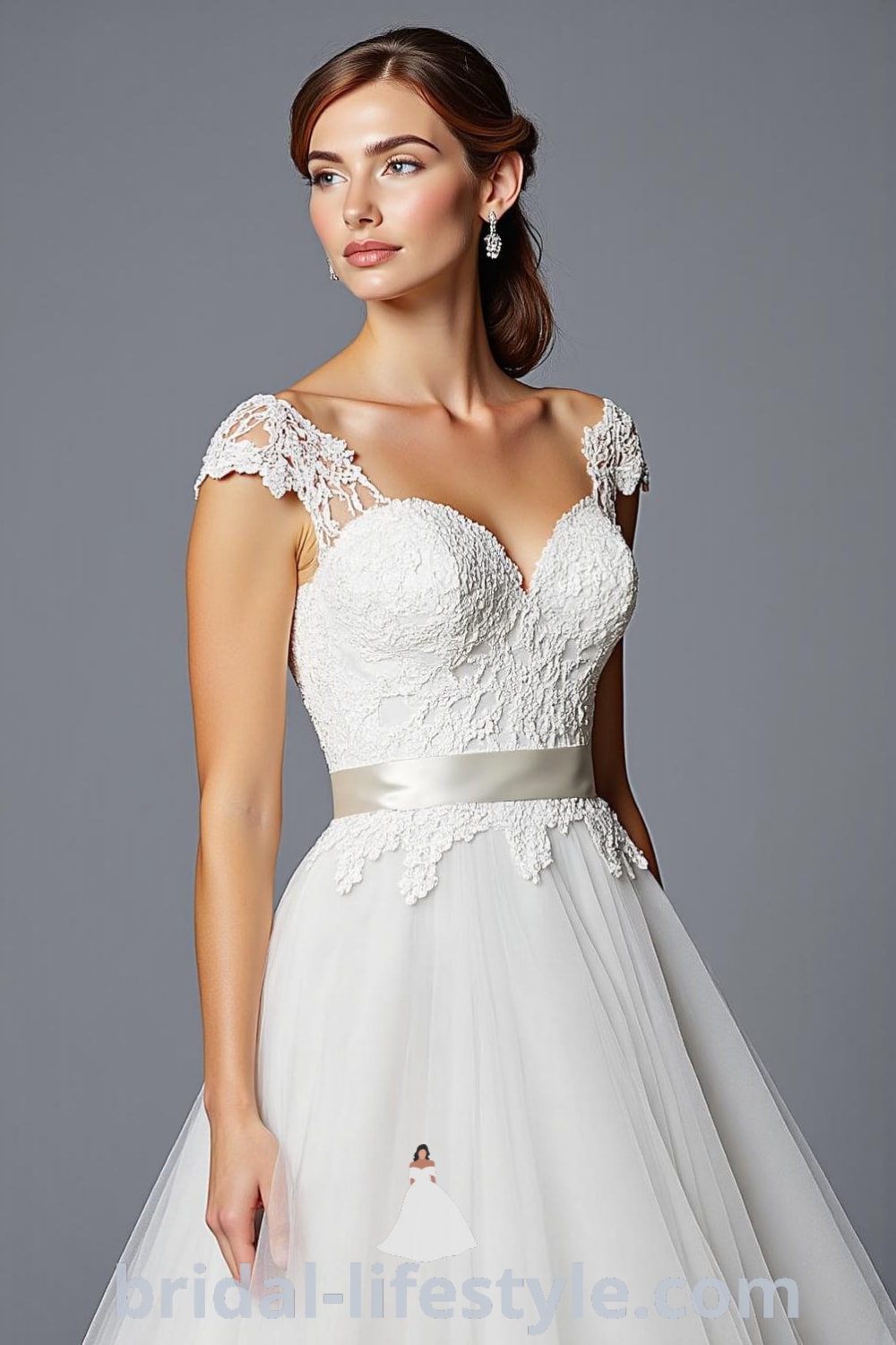 A fitted bodice wedding dress adorned with intricate lace appliqués, featuring a voluminous tulle skirt, sweetheart neckline, and cap sleeves, completed with a satin waistband. bridal-lifestyle.com