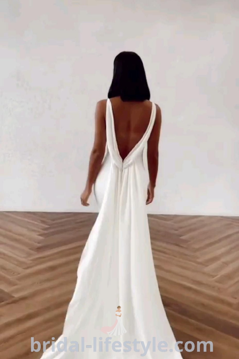 An elegant low back wedding dress in a beautiful empty room with wood flooring, designed for brides seeking a classy and romantic look. Featuring a sweetheart neckline with sleeves, this backless gown is ideal for the special day. Discover more wedding dress inspirations at bridal-lifestyle.com.