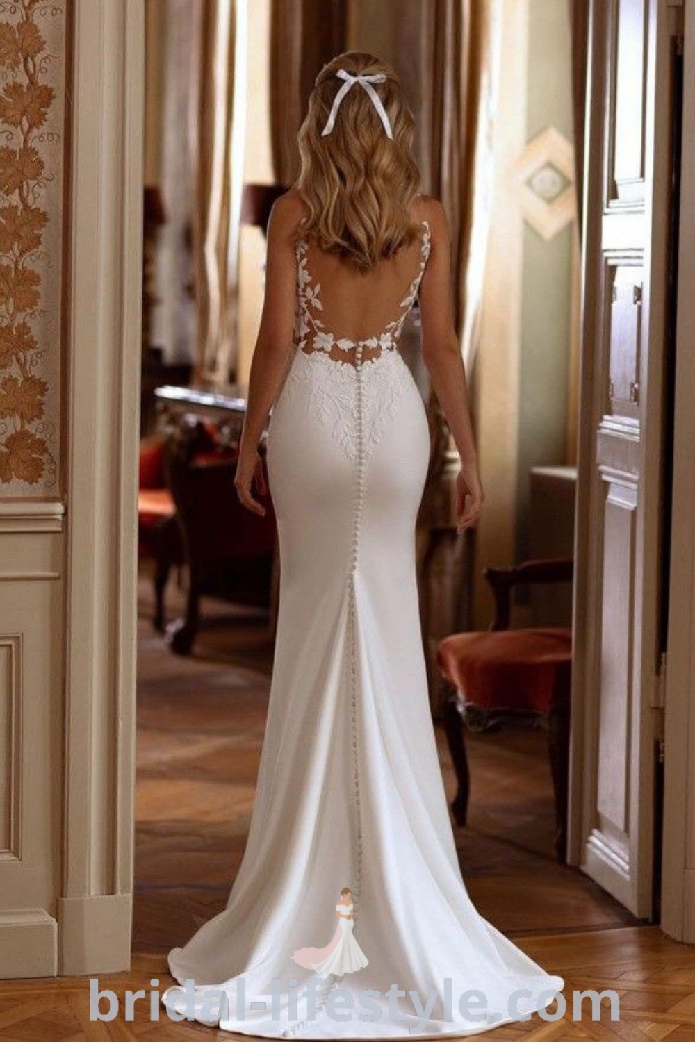 An elegant backless wedding dress with detailed back design, featuring buttons and a low drape, perfect for dreamy brides. Ideal for every unique taste, this beautiful gown embodies romance and style for the special day. Find inspiration and the best aesthetic ideas at bridal-lifestyle.com.