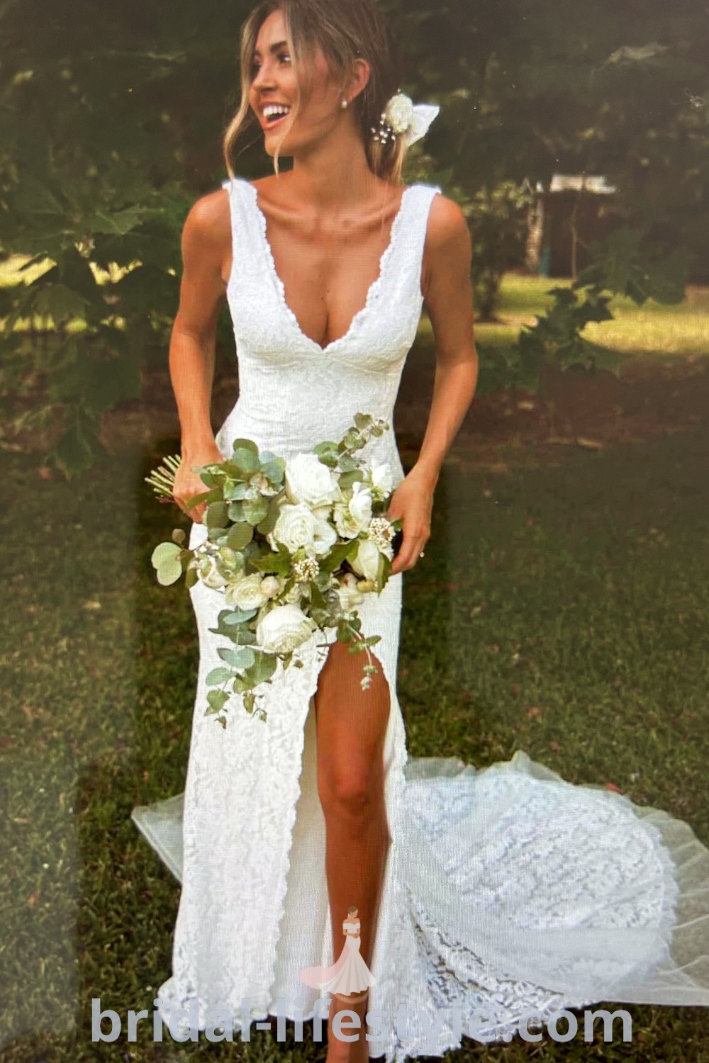 An elegant woman in a white wedding dress holding a bouquet, posing with her legs crossed, showcasing a romantic look perfect for beach weddings or Bali ceremonies, with subtle lace and dreamy design elements. Discover more wedding dress inspiration at bridal-lifestyle.com.