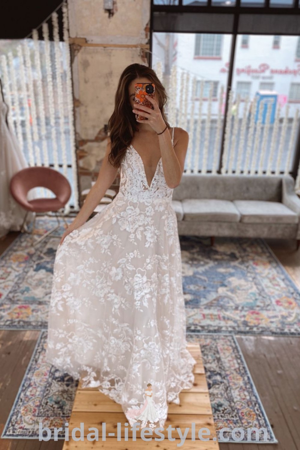 A woman in an elegant Elsie Flowy Wedding Dress taking a selfie while standing on a wooden platform, showcasing a flowy boho aesthetic ideal for brides or bridesmaids. This stunning look fits perfectly into a wedding vision board. Discover the best wedding dress ideas at bridal-lifestyle.com.