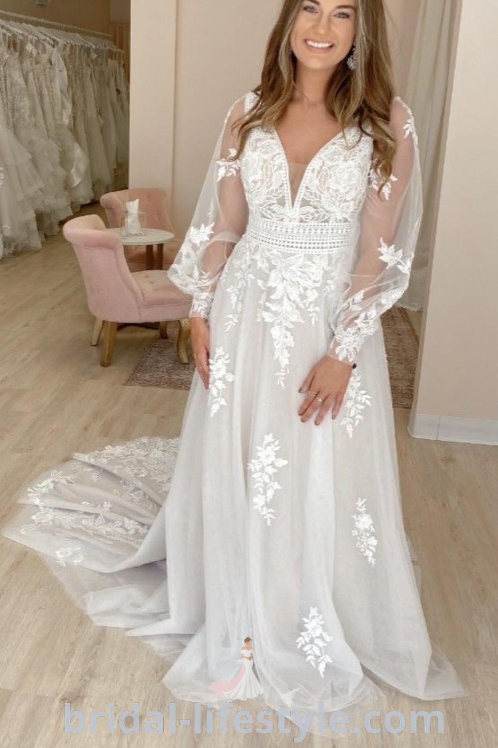A woman standing in front of a mirror wearing a stunning white wedding dress with sheer sleeves and floral appliques, ideal for curvy brides. This aline gown combines elegance and comfort, perfect for boho bridal looks on the special day. Explore more at bridal-lifestyle.com.