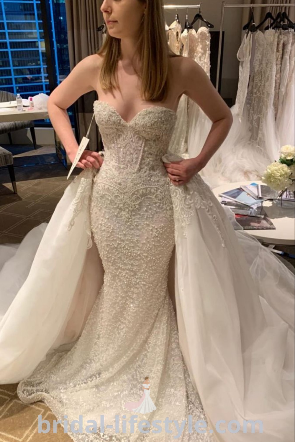 An elegant woman standing in front of a stunning Julie Vino wedding dress, showcasing its romantic details and trends for dreamy brides. This image captures inspiration for bridal shoots and wedding planning ideas found on bridal-lifestyle.com.