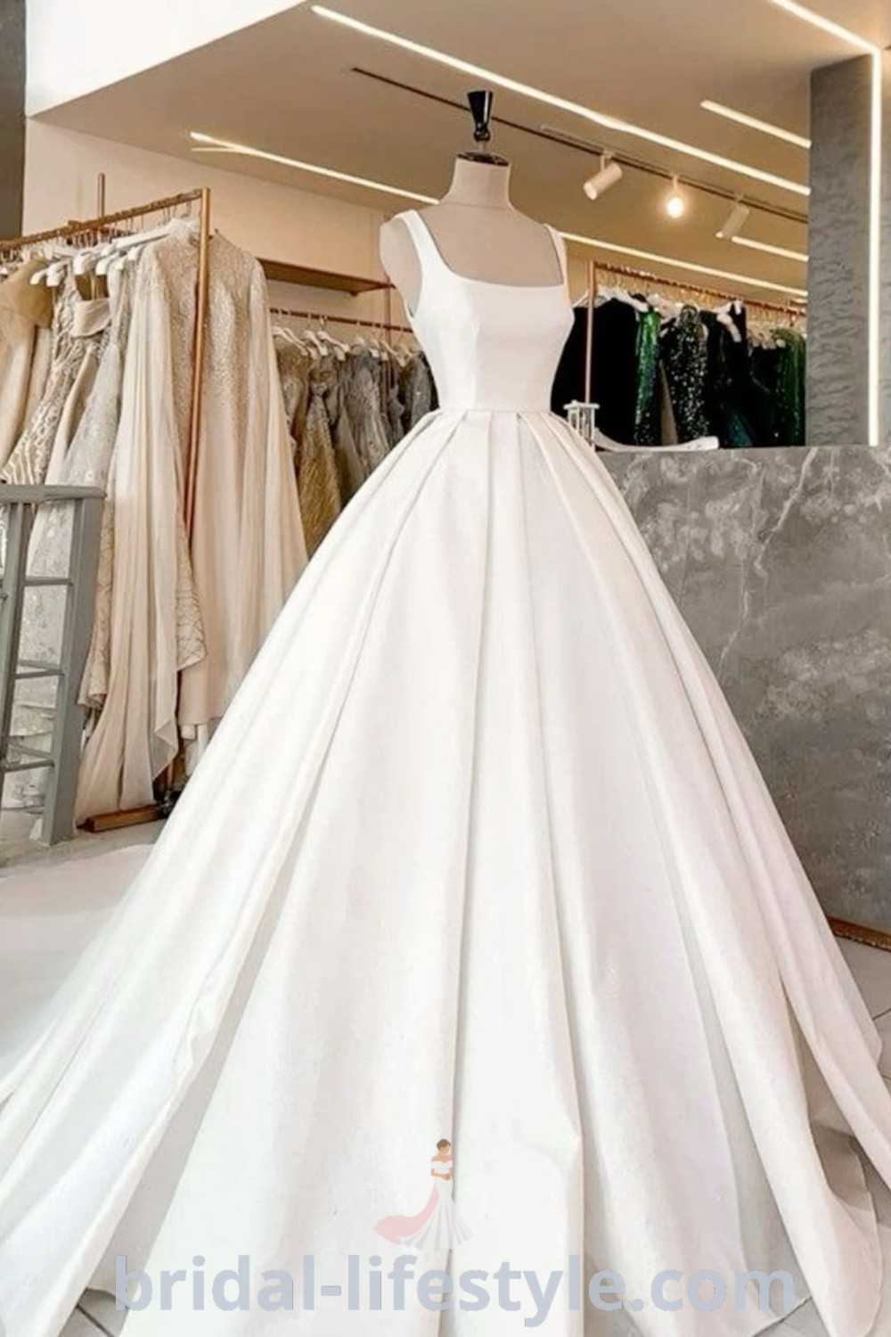 An elegant white wedding dress displayed in a store, featuring a matte satin finish, square neck, and ball gown style. Ideal for dreamy brides searching for the best aesthetic ideas for their special day. Discover dresses that embody elegance and charm at bridal-lifestyle.com.