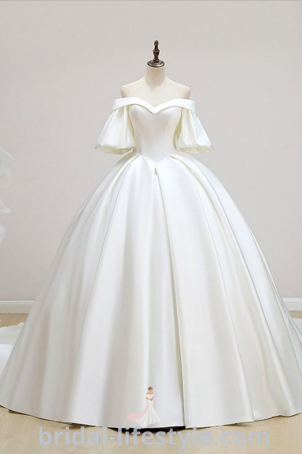 An elegant white ball gown displayed amidst mannequins and flowers, showcasing a wedding dress satin with short sleeves and chapel train details, ideal for dreamy brides. Explore more styles and inspiration at bridal-lifestyle.com.