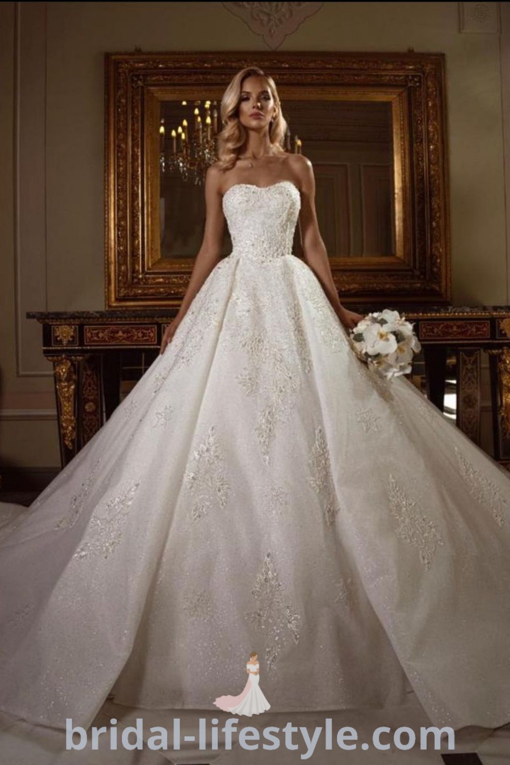 An elegant woman in a massive princess wedding dress stands next to a mirror, showcasing the poofy gown