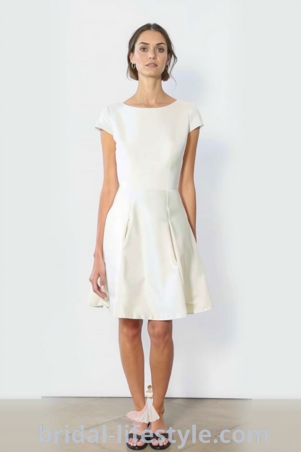 Refined short wedding dress with structured silhouette, smooth satin fabric, delicate cap sleeves, and simple neckline, perfect for a chic ceremony. bridal-lifestyle.com
