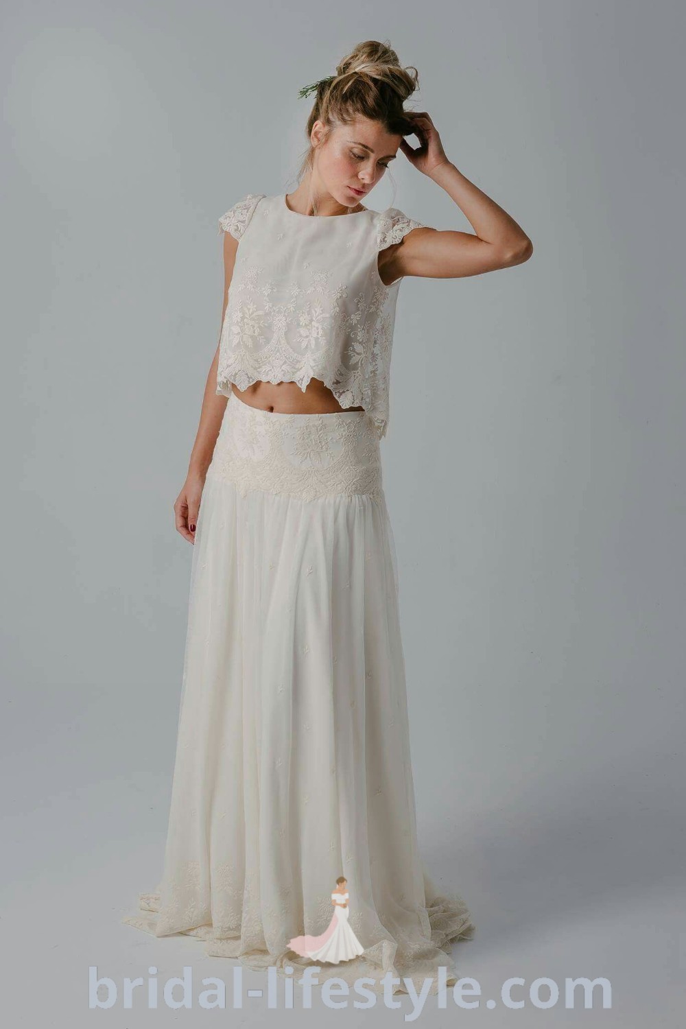 A woman in a white dress, part of an elegant bridal skirt separate, stands with her hands on her head, looking down. This romantic look is ideal for wedding ceremony dresses, featuring stylish wedding skirts and tops that reflect every bride