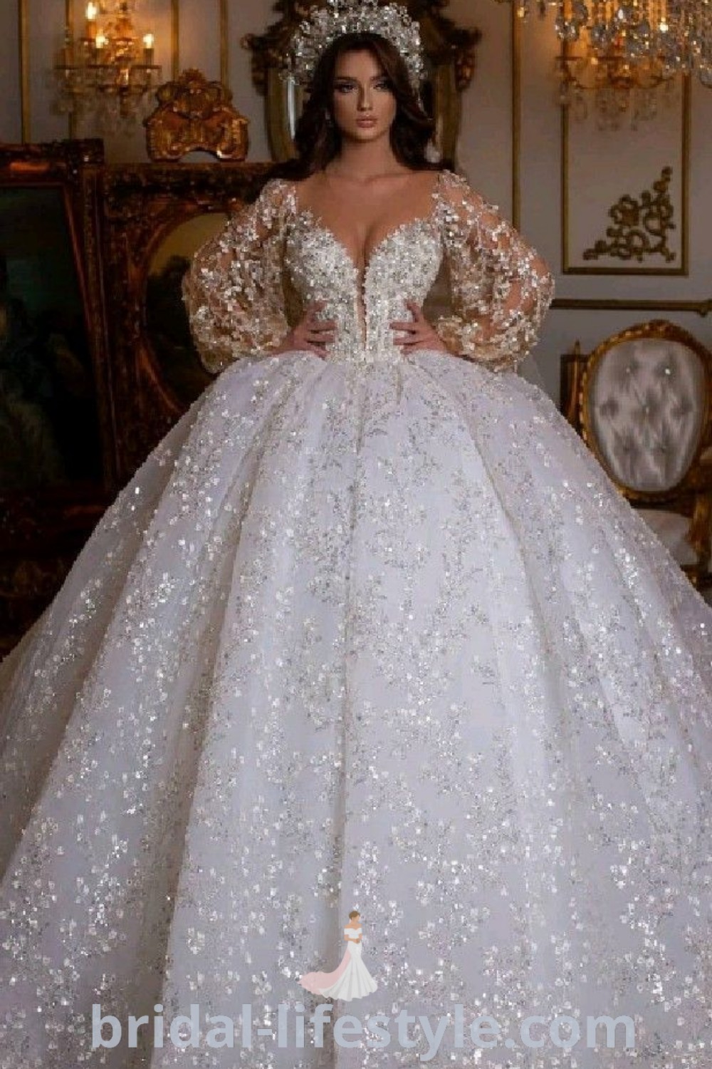 An elegant woman in a white wedding dress with a lace-up back, standing beside a chandelier, showcasing the best in bridal fashion. This beautiful ball gown wedding dress with long sleeves and beading offers romantic inspiration for dreamy brides and unique tastes. Discover more bridal ideas at bridal-lifestyle.com.