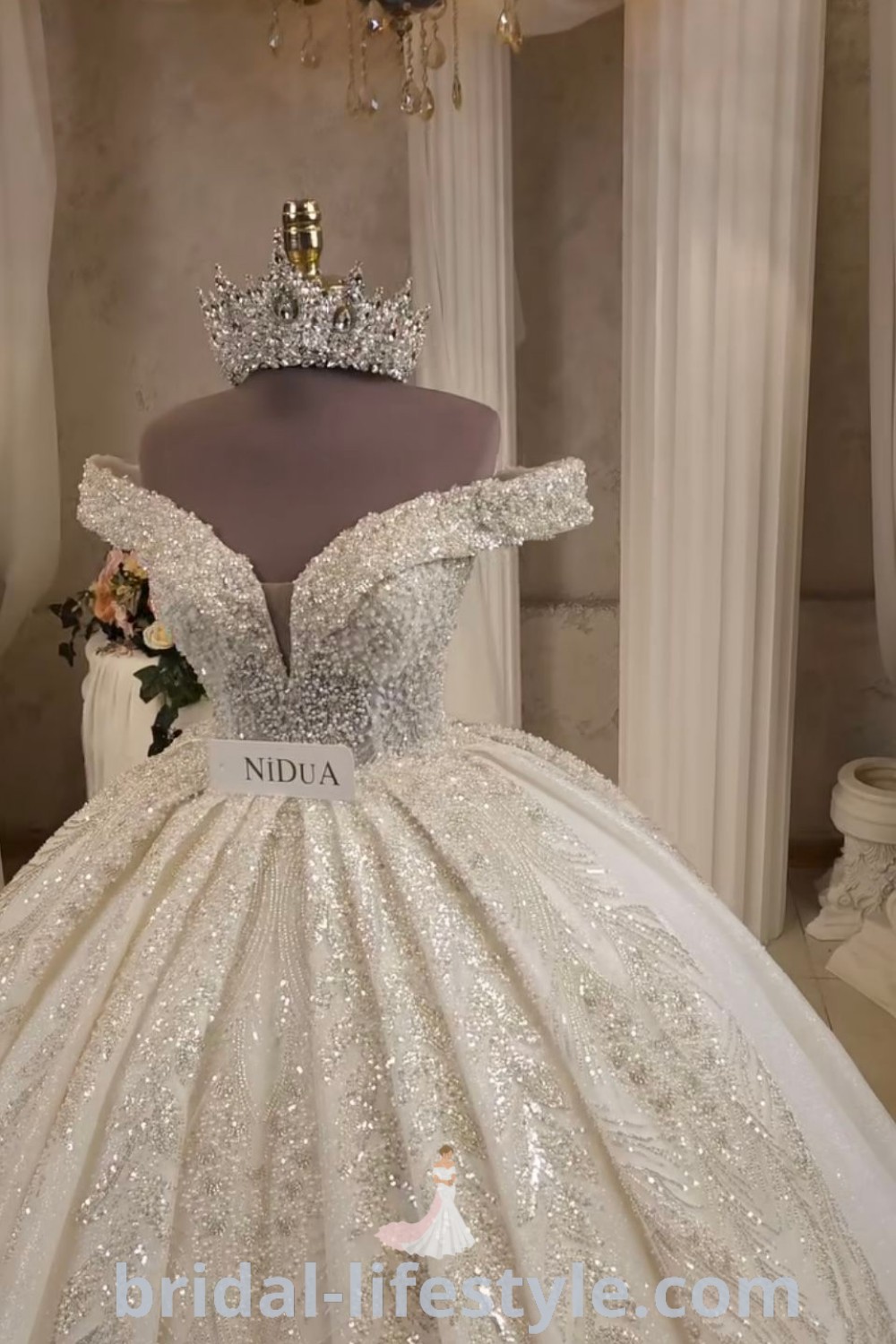 An elegant wedding dress showcased under a chandelier, featuring puffy design and sparkling rhinestones, ideal for brides seeking beautiful wedding dresses and royal wedding gowns inspiration. Discover dreamy styles and aesthetics at bridal-lifestyle.com.