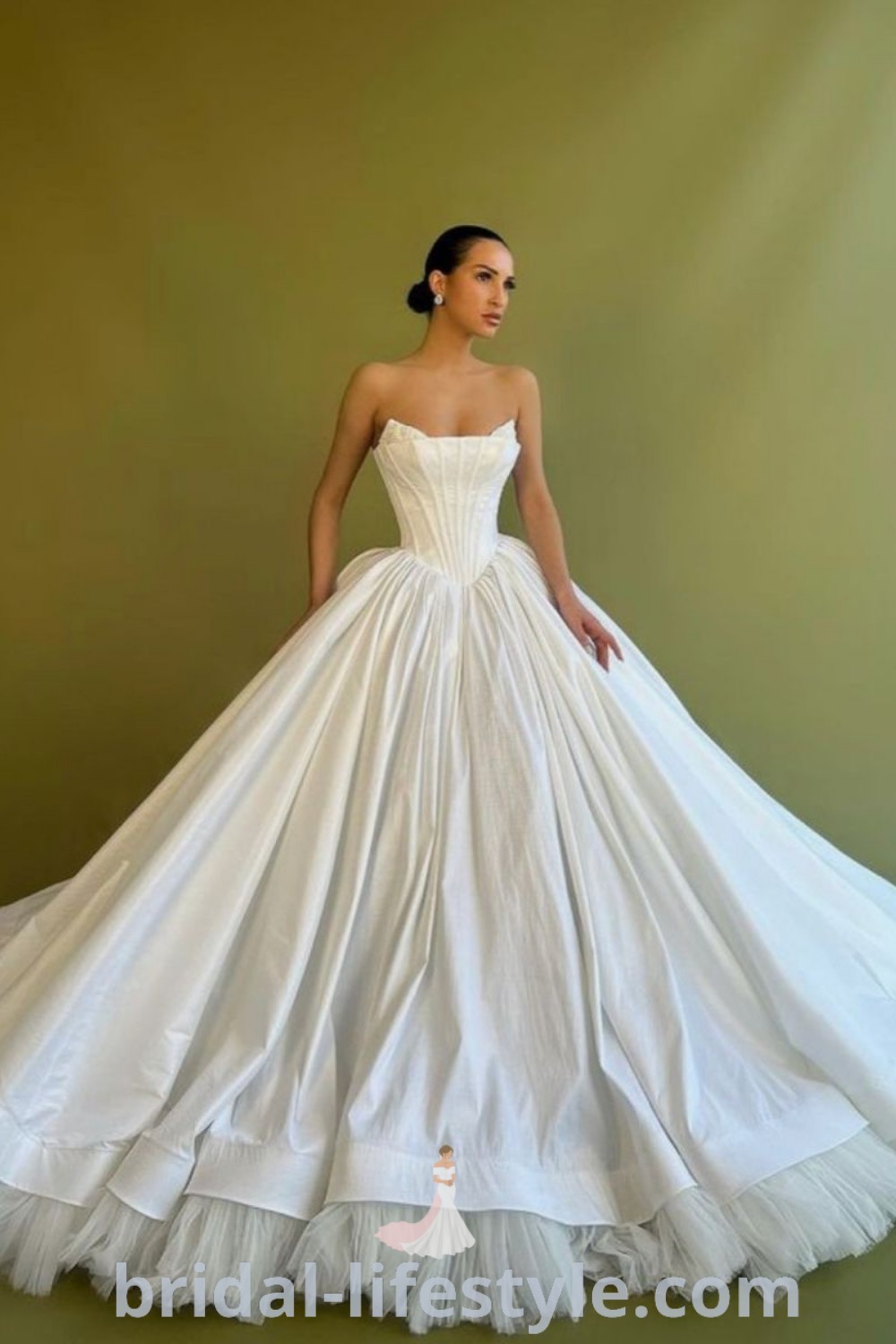 A woman in a white dropped waist ball gown wedding dress, embodying elegant bridal aesthetic ideas and the latest trends for 2023. Perfect for dreamy brides seeking inspiration for their special day, featured on bridal-lifestyle.com.
