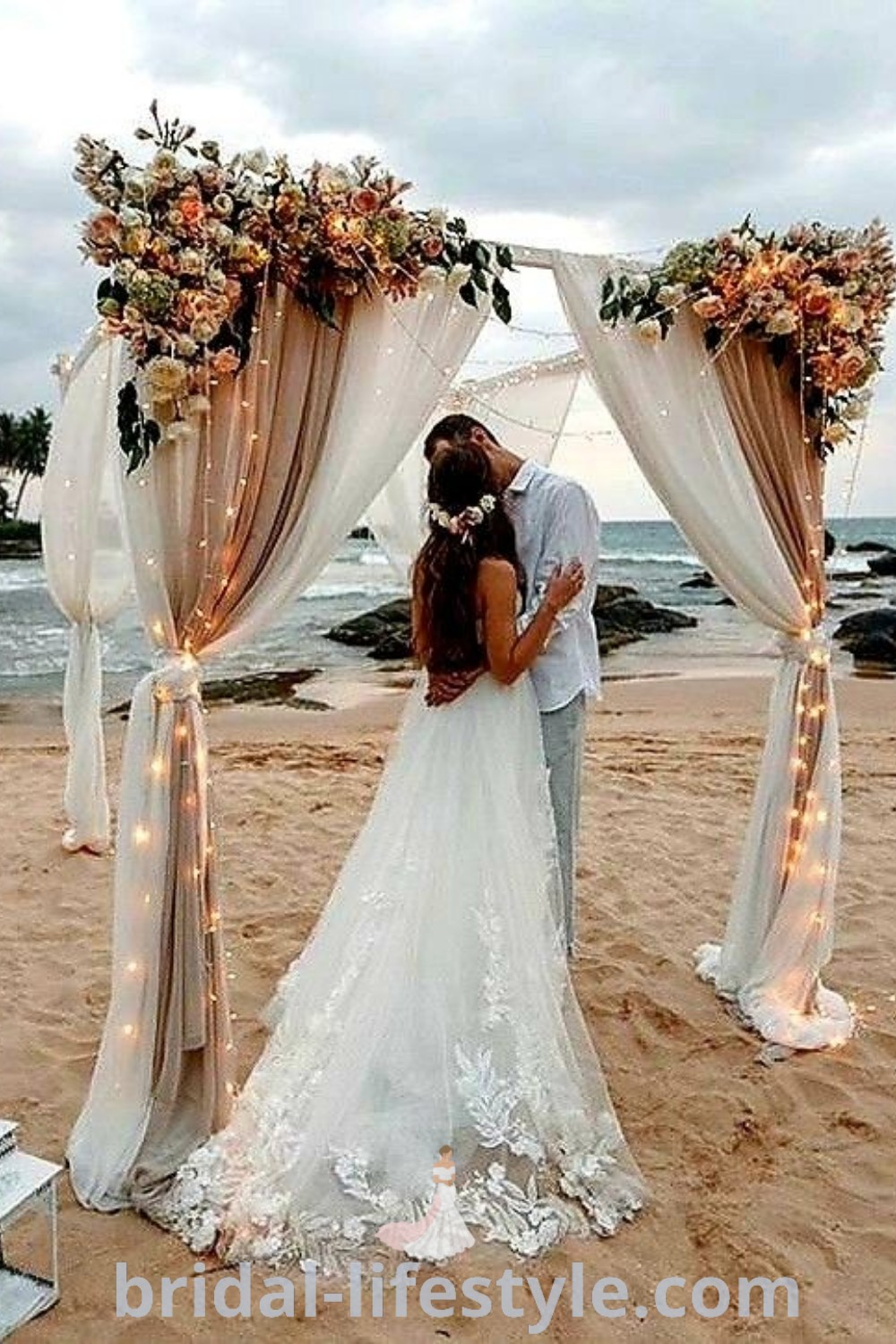 A romantic beach wedding scene featuring a bride and groom kissing in front of a flower-decorated wedding arch. This dreamy setup captures the essence of a small beach wedding, perfect for every bride