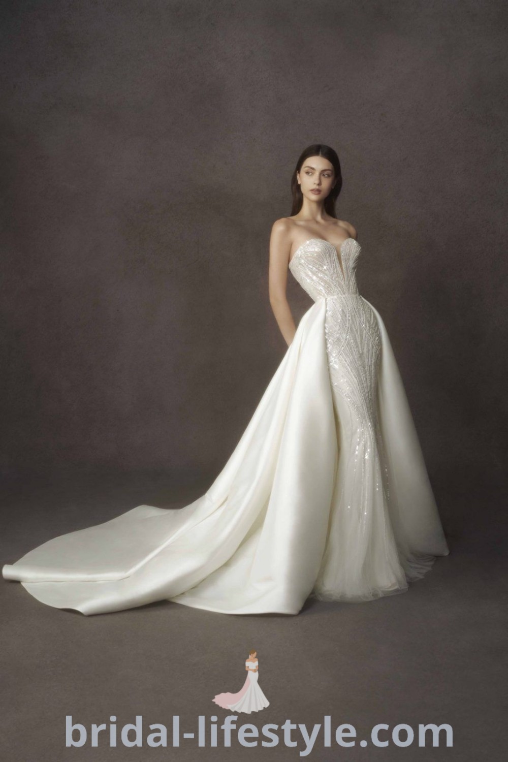 A woman in a beautiful white wedding dress poses with her hands on her hips, showcasing elegance and style. This image serves as inspiration for dreamy brides seeking the best dresses of their dreams for their special day. Explore more bridal aesthetic ideas at bridal-lifestyle.com.