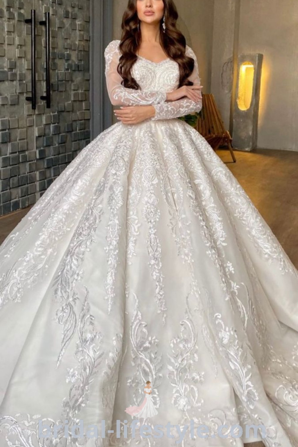 An elegant woman in a white wedding dress poses for the camera, showcasing an exquisite long sleeve bridal gown that