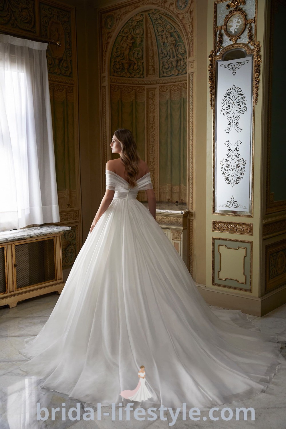 A woman in an elegant white wedding dress ballgown is poised near a window, embodying romance and dreams for every bride