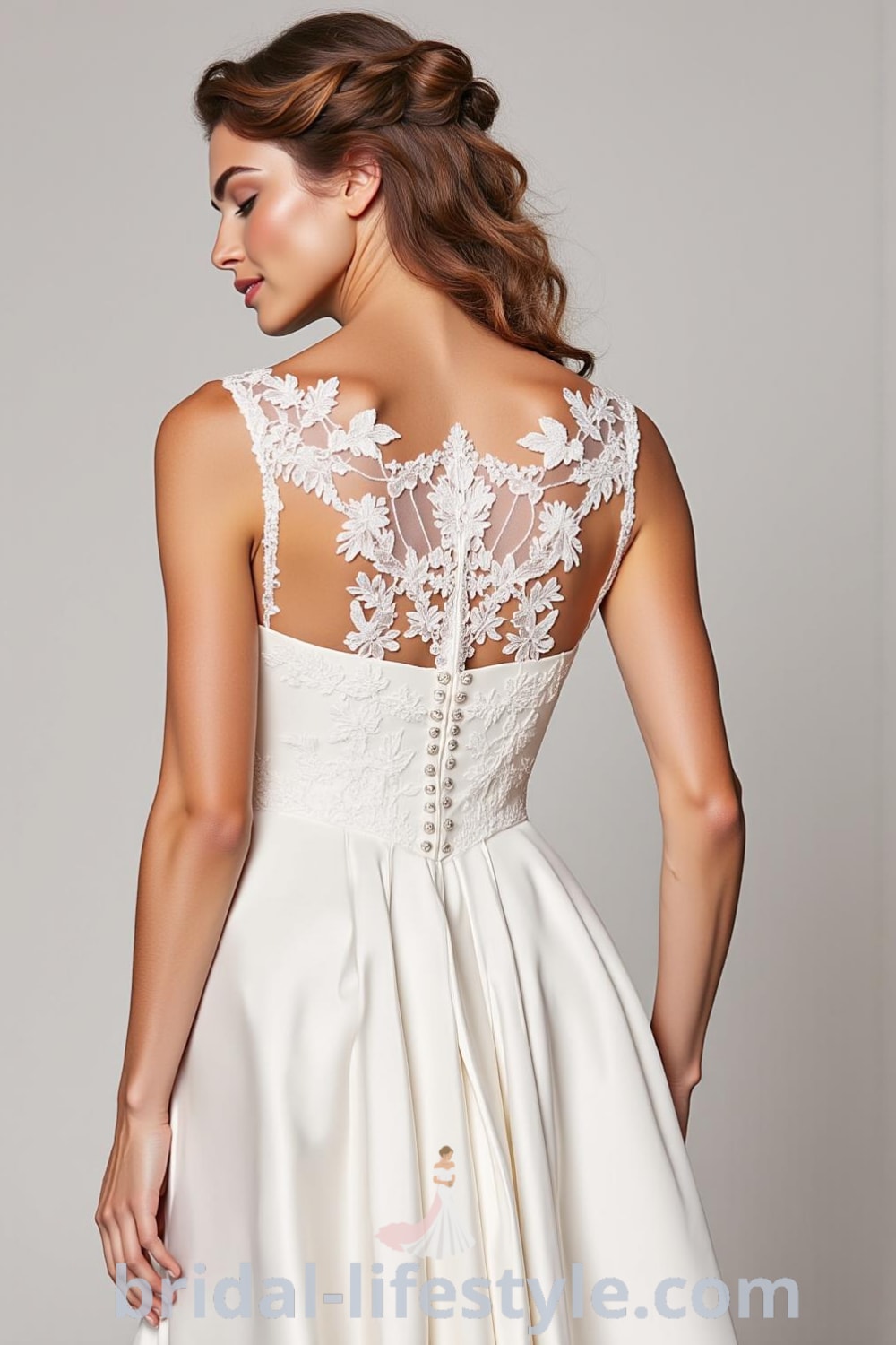 A-line wedding dress made of luxurious satin with a boat neck design, floral lace appliqués, and a flowing skirt, featuring a row of covered buttons at the back. bridal-lifestyle.com