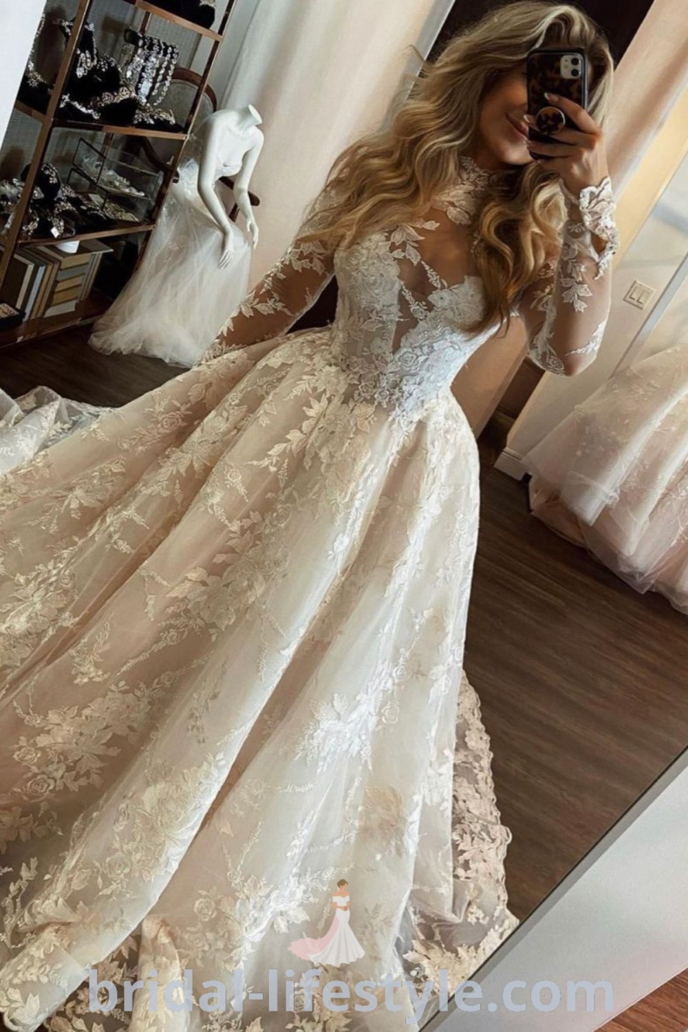 A woman taking a selfie in her elegant wedding dress while looking in the mirror. The long sleeve lace gown represents trending wedding dresses, offering dreamy aesthetics for every bride’s unique taste. Discover the best wedding dress ideas and inspiration at bridal-lifestyle.com.