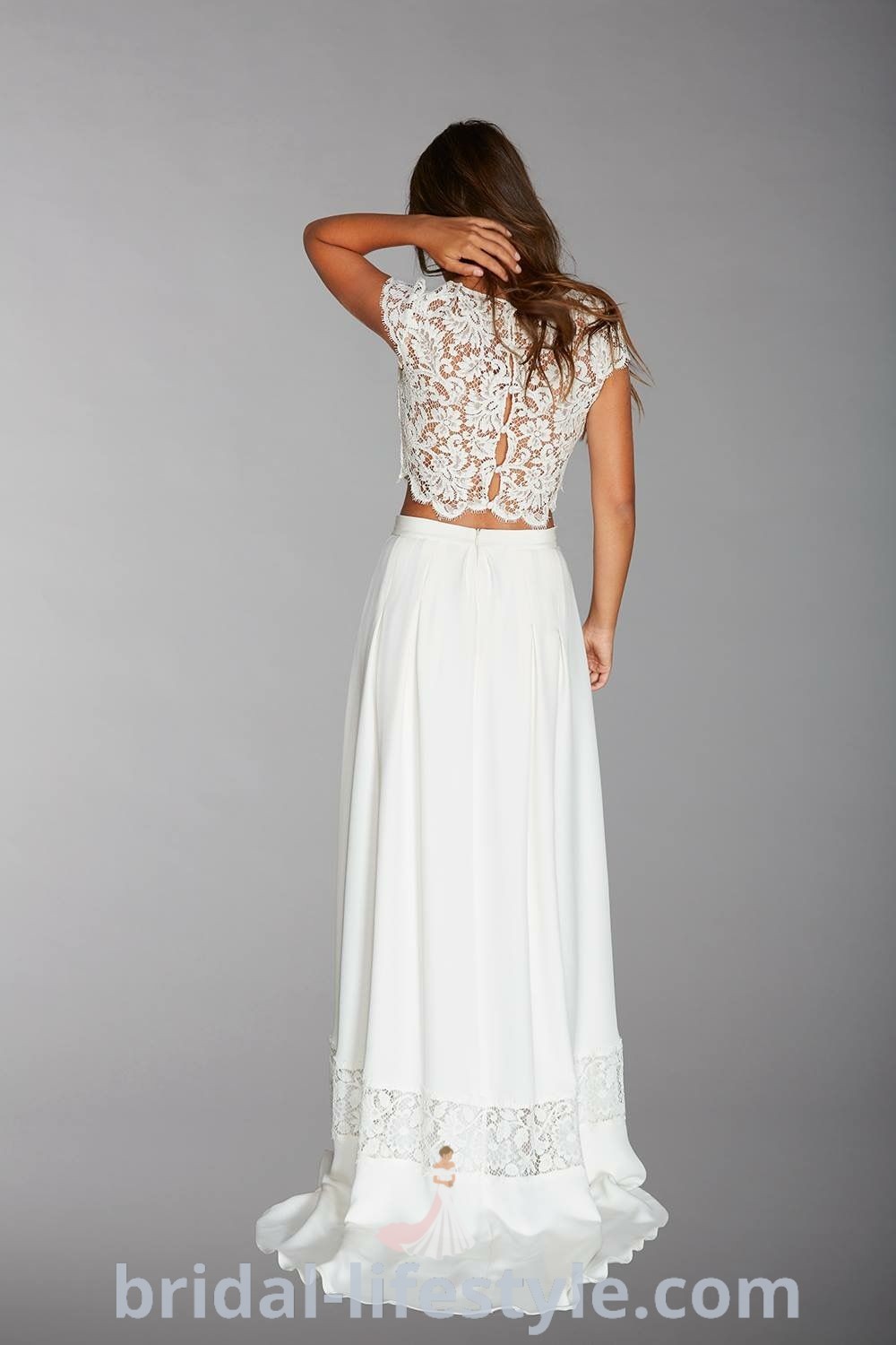 A woman wearing an elegant two piece wedding dress, featuring a lace top and flowing skirt, ideal for classy brides. This design embodies romantic and elegant aesthetic ideas for the special day, providing versatility in bridal fashion. Discover more inspiration looks for dreamy brides at bridal-lifestyle.com.