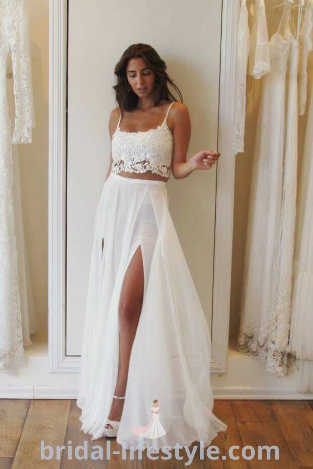 A woman standing in front of a mirror wearing a white two-piece skirt and crop top, ideal for a vow renewal ceremony. This outfit combines elements of elegance and trendy bridal styles, perfect for a tropical wedding celebration. For more inspiration on unique bridal looks, visit bridal-lifestyle.com.