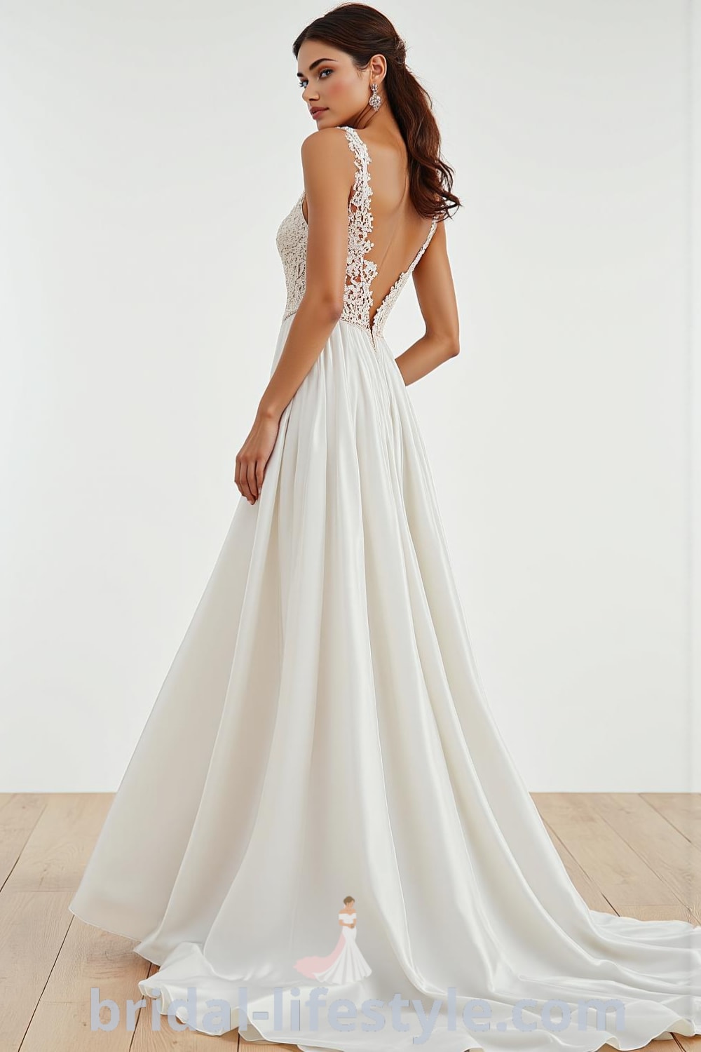 A-line wedding dress with boat neck, luxurious satin fabric, flowing skirt, delicate lace appliqués on the bodice, and structured back with buttons. bridal-lifestyle.com